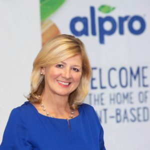 Sue Garfitt wearing a blue shirt in front of an Alpro banner.