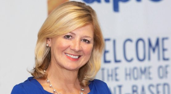 Sue Garfitt wearing a blue shirt in front of an Alpro banner.